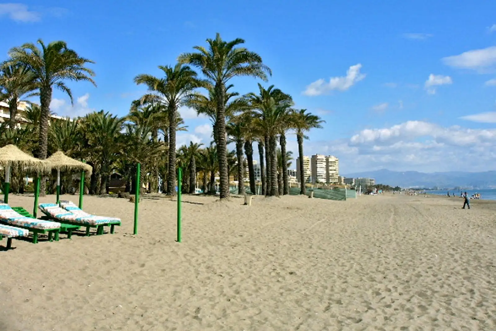 dos hamcas mirando al mar con una playa siendo la de Torremolinos y al final se ven 3 torres que son las torres de playamar y tambien hay un pequeña zona de palmeras al lado del mar. Prepara tú negocio en temporada alta en Torremolinos