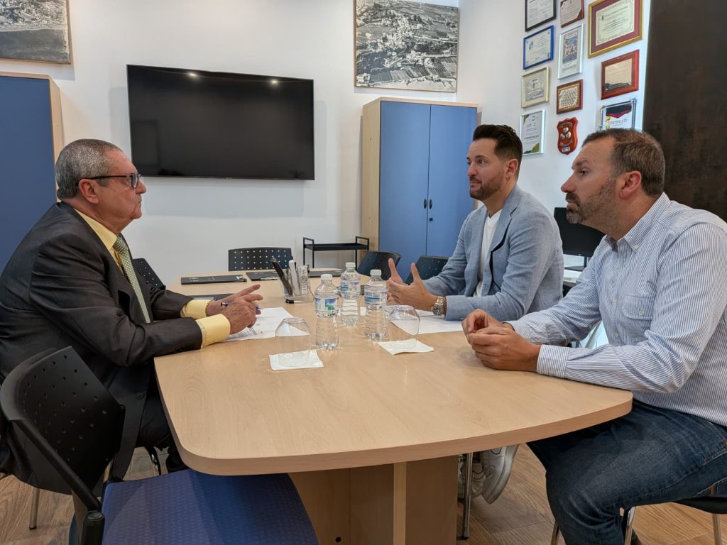 Una mesa central, a la derecha 2 hombres bien vestidos de iPrevencion. A la izquierda el Presidente Ejecutivo de la Asociacion de Comerciantes y Empresarios de Torremolinos Juan Vallejo. Firmando el Convenio de iPrevención